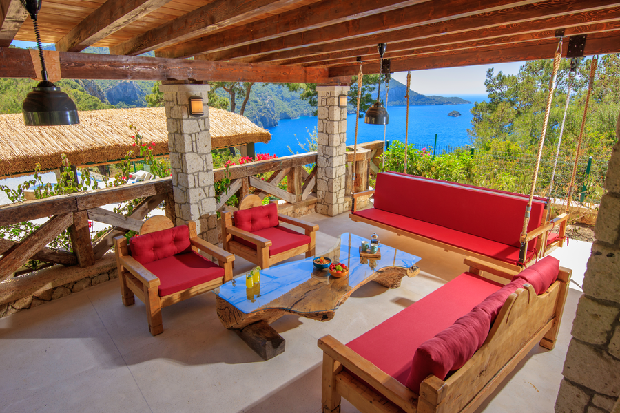 Sea-view terrace lounge with handcrafted wood furniture and red cushions