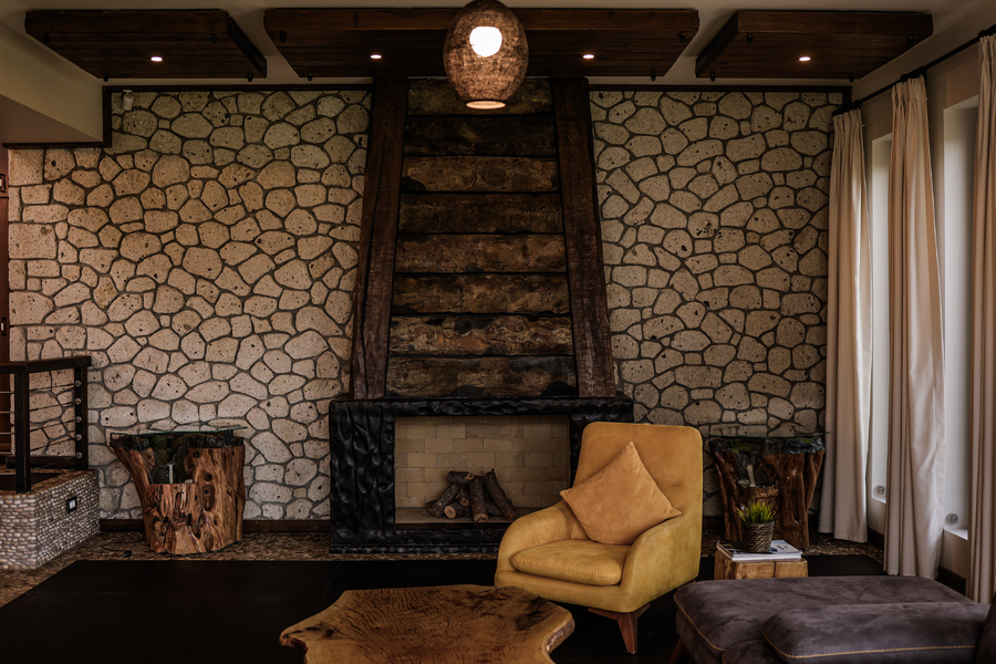 Rustic stone-wall living room with handcrafted fireplace and natural textures