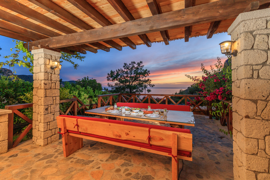 Sunset terrace dining table overlooking Mediterranean sea and forested coastline